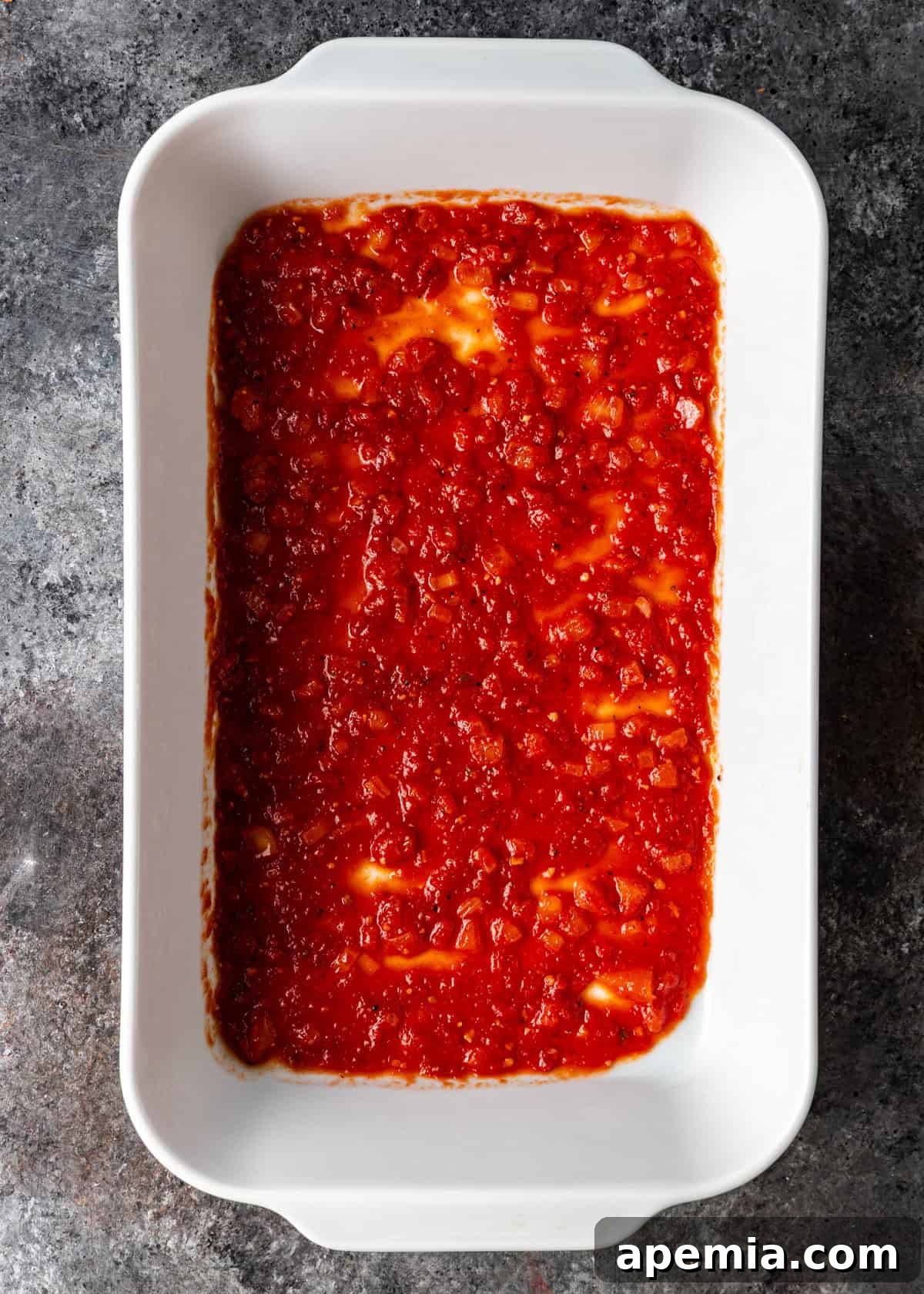 overhead process shot: white baking dish with sauce in bottom