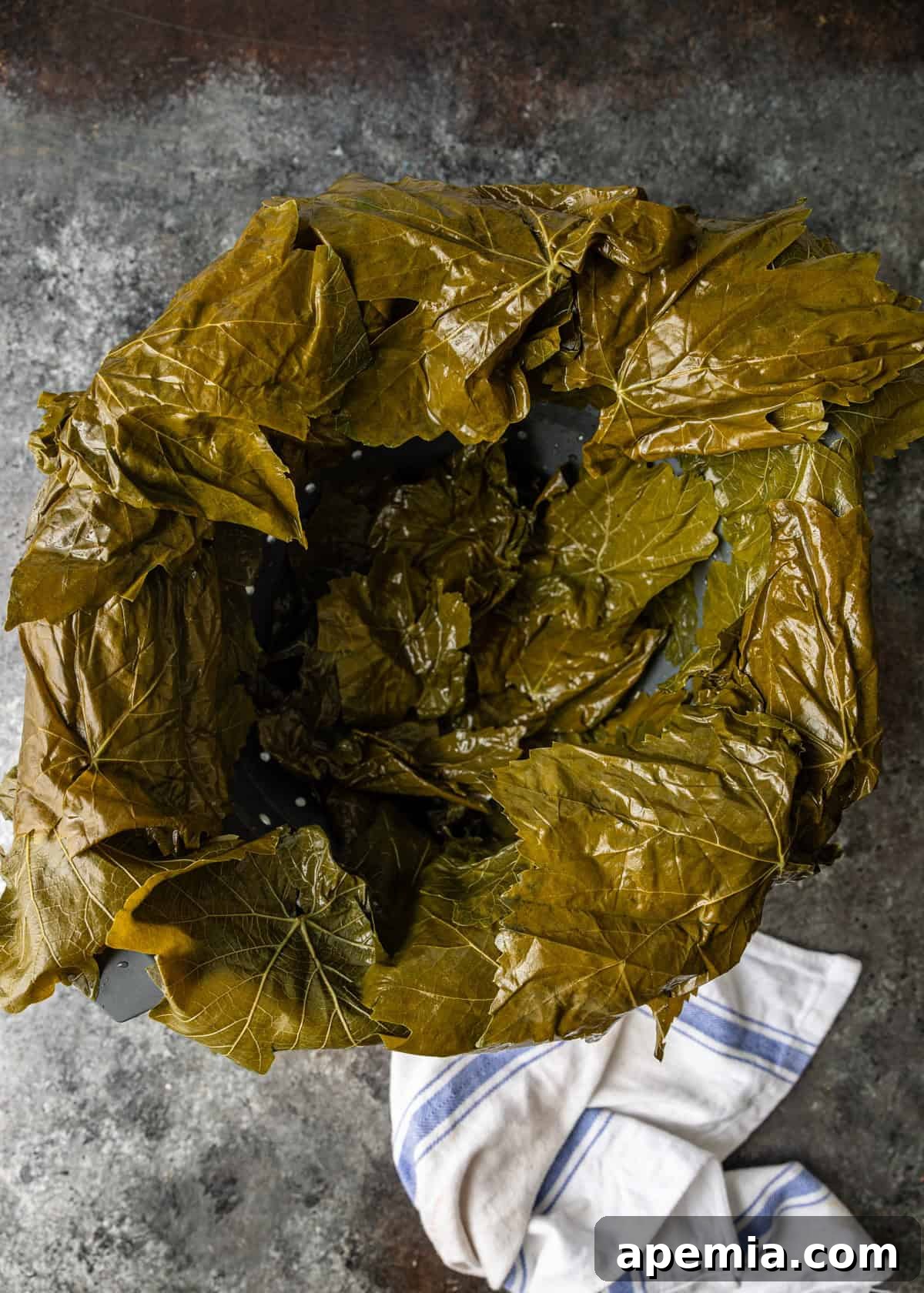 overhead process shot: circle of grape leaves on counter with tea towel off to side