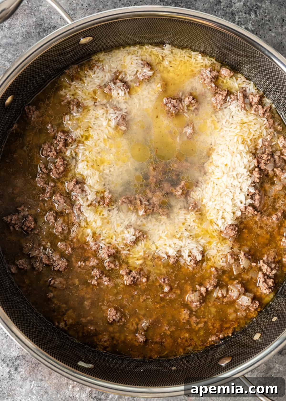 overhead process shot: rice and water added to ground beef and onions in deep skillet