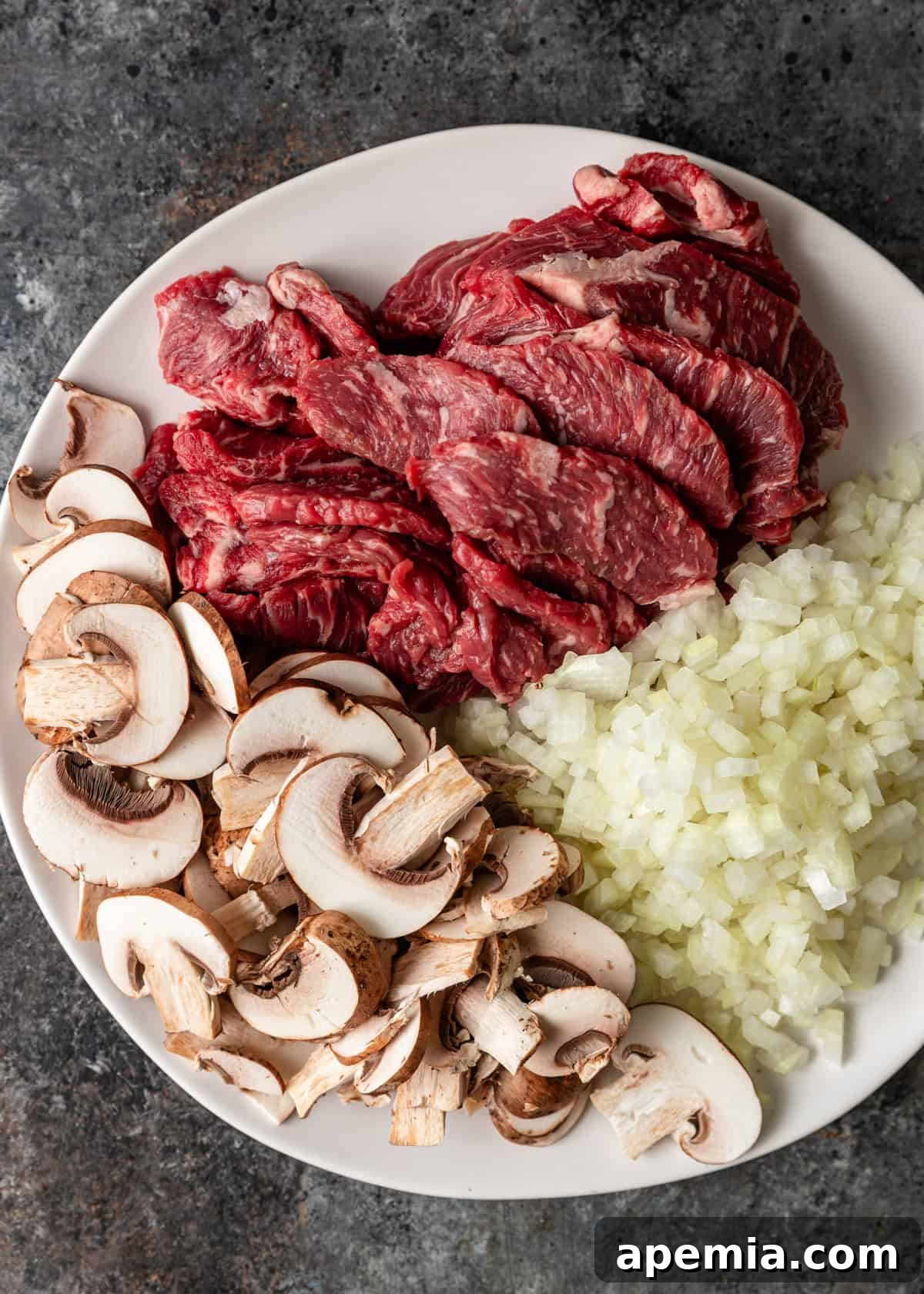 overhead process shot: sliced meat, mushrooms and diced onions on white plate