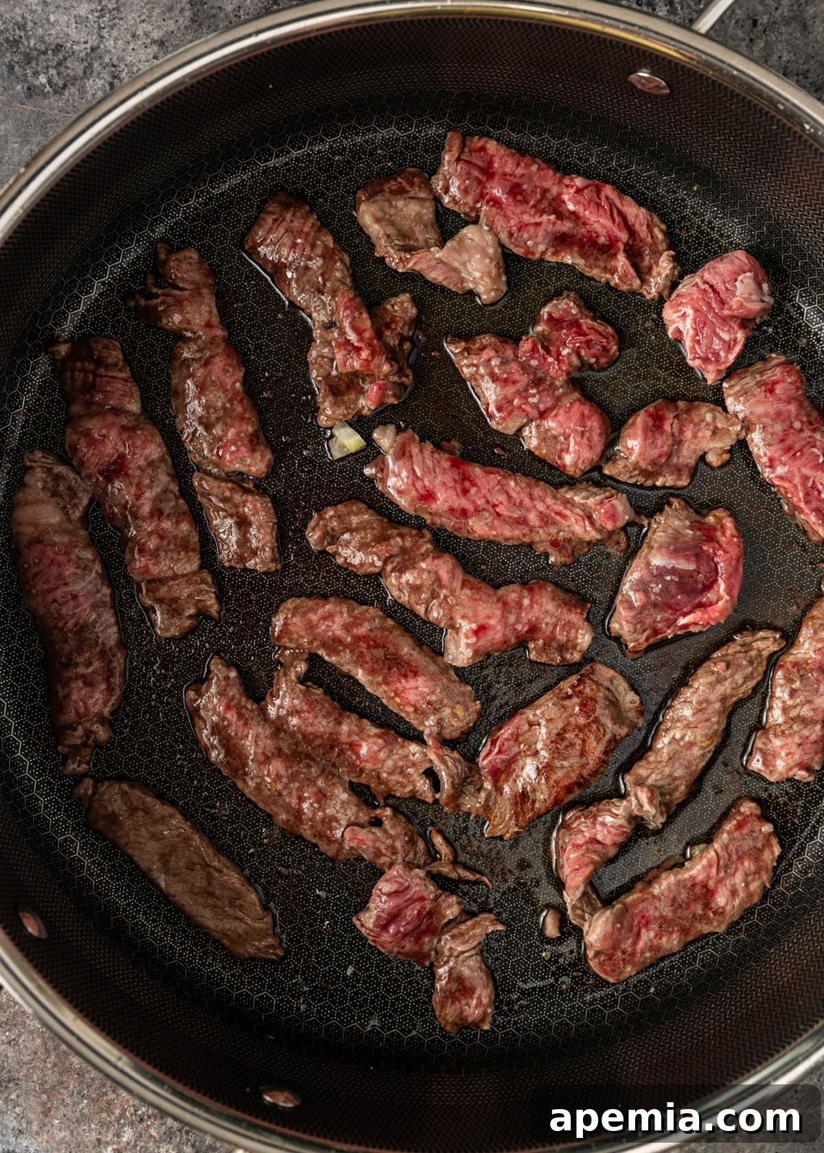 overhead process shot: sliced meat cooking in skillet