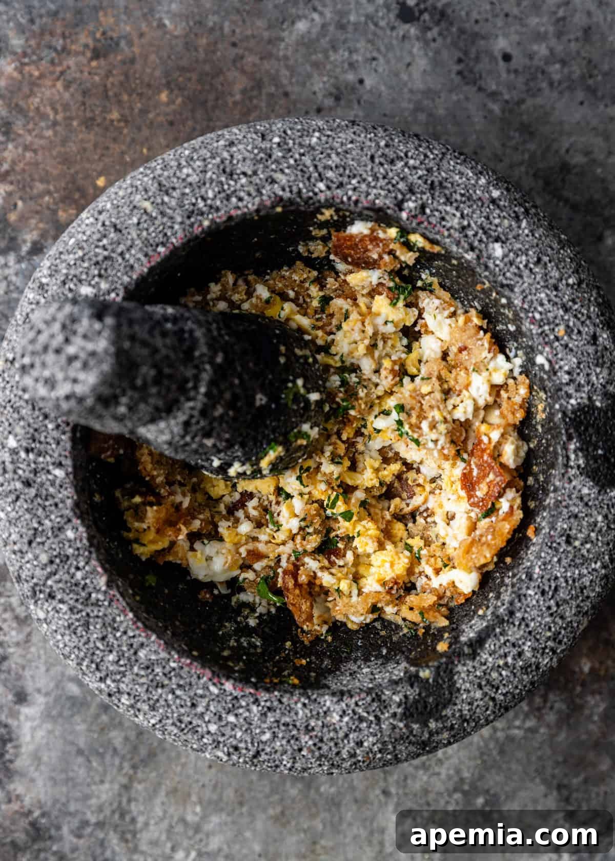 closeup overhead process shot: mashed fried egg and parsley in mortar