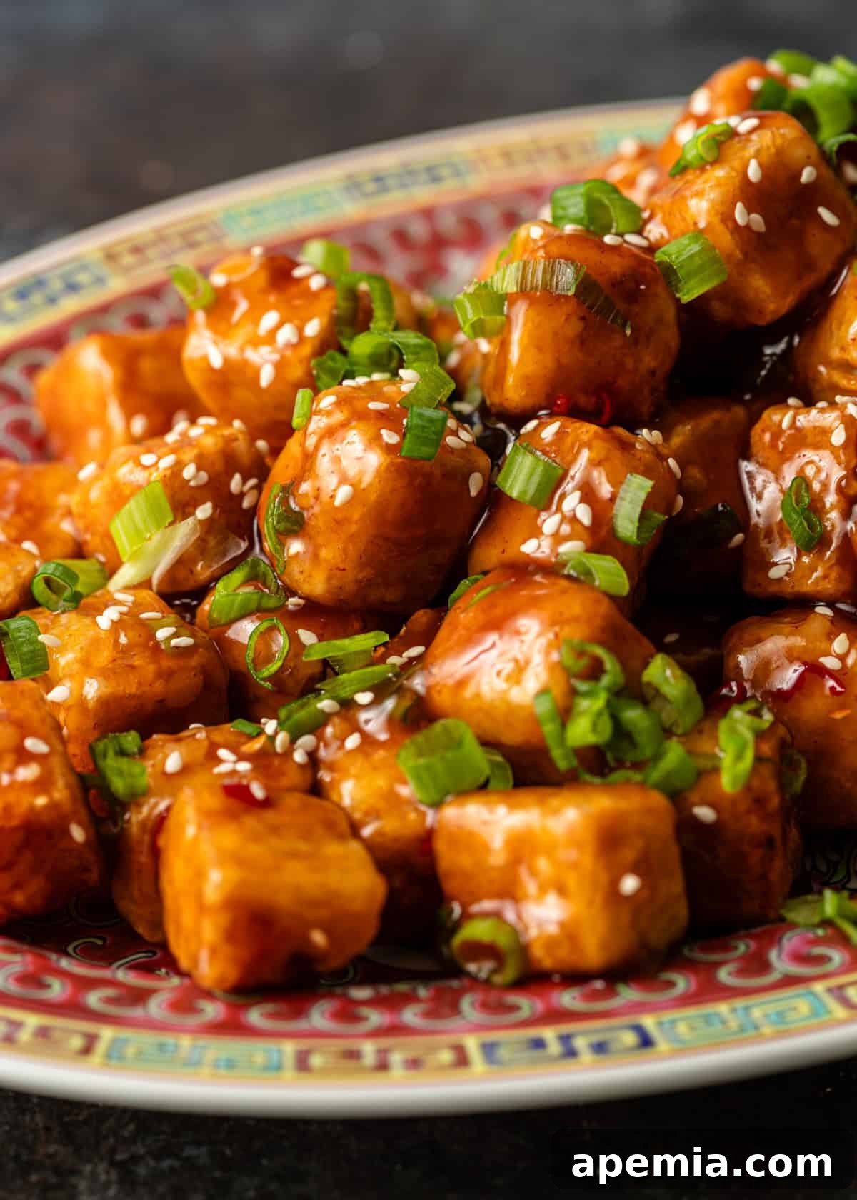 closeup side view: tofu stir fry topped with green onions and sesame seeds