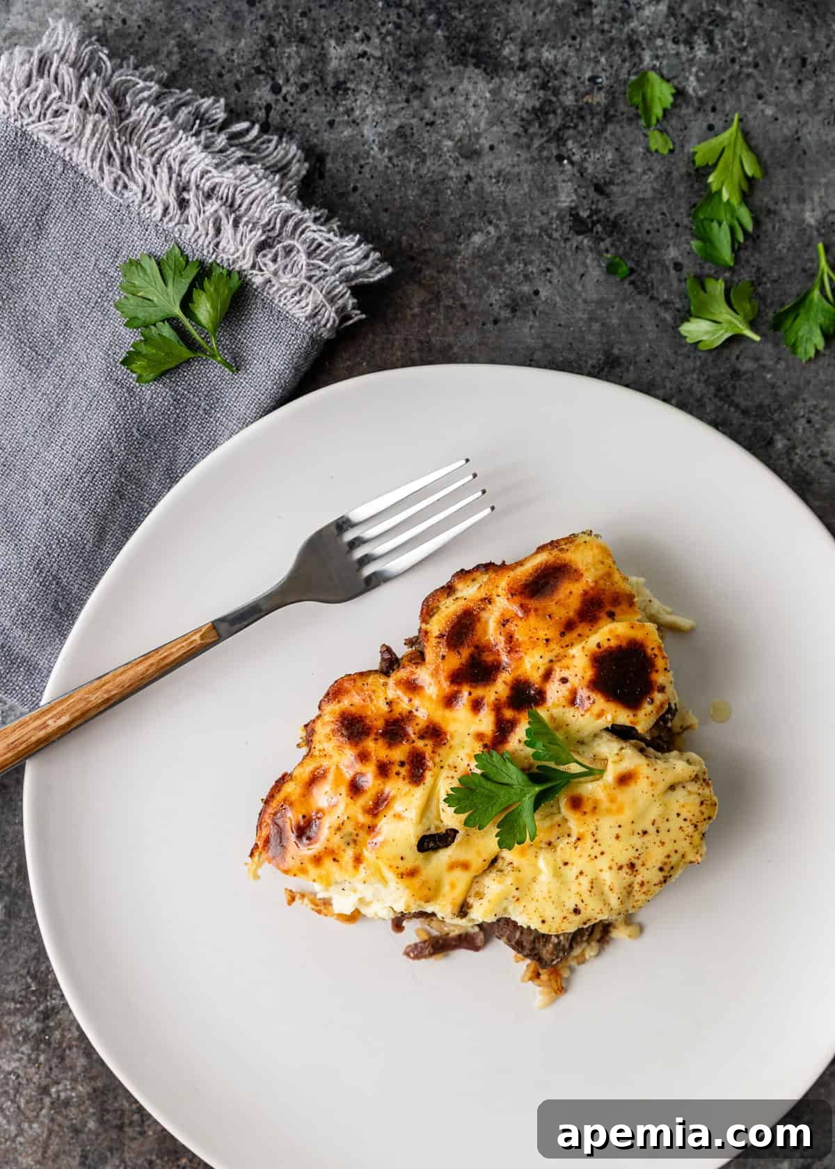 closeup overhead: baked lamb and rice on white plate with fork 