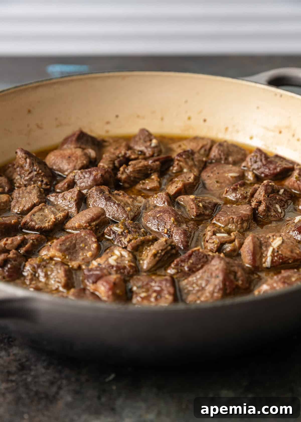closeup side view: cooked lamb cubes in skillet