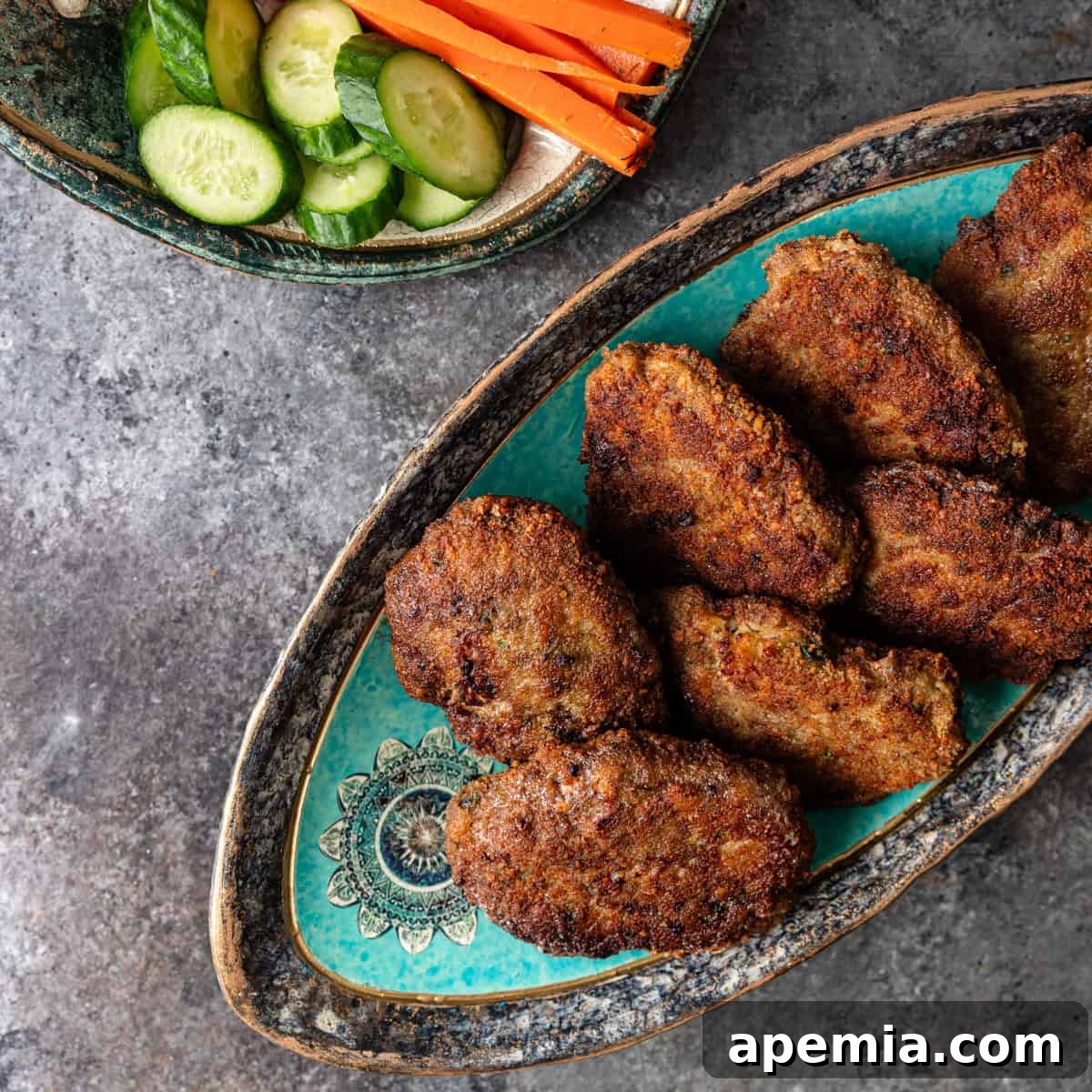 overhead view: persian meat patties on serving dish and another dish with cucumbers and carrots