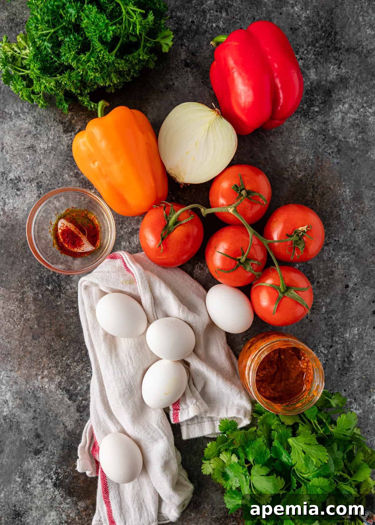 whole eggs, fresh tomatoes, colored bell peppers and other ingredients for making a shakshuka recipe