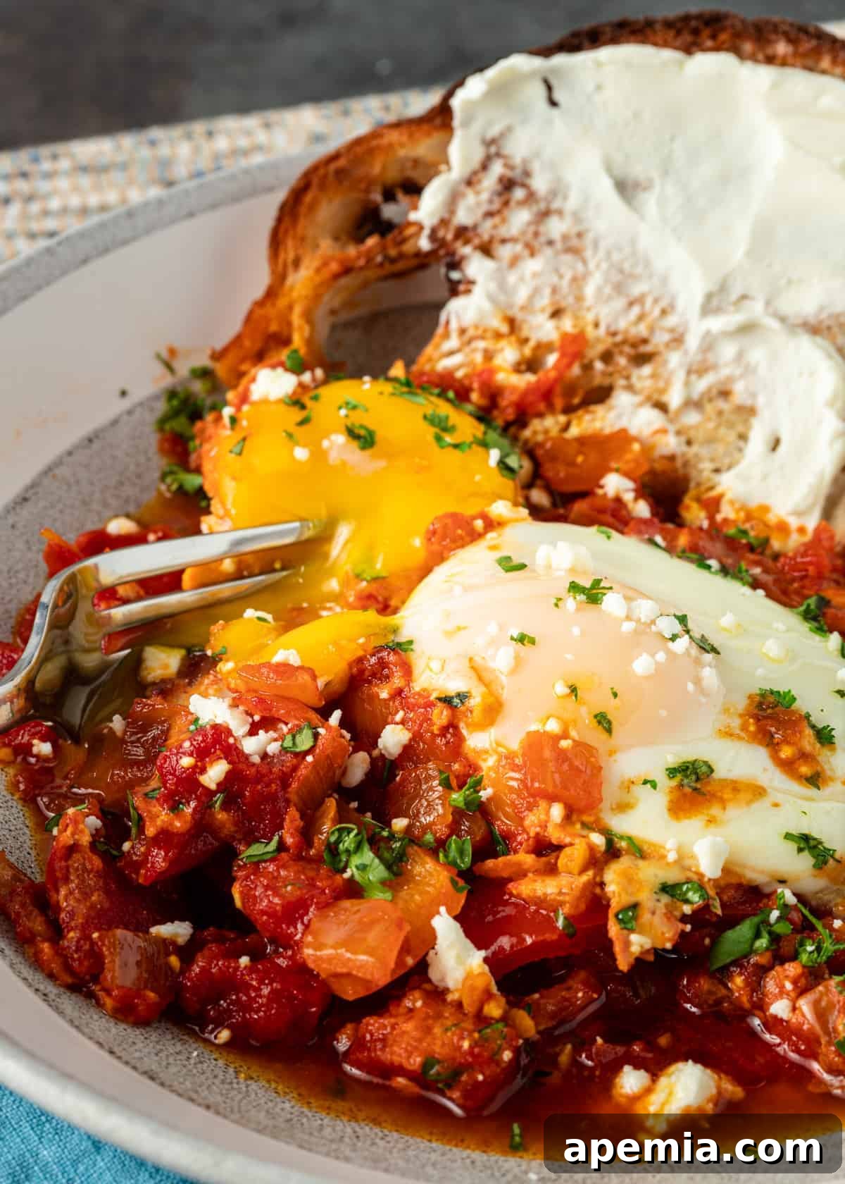 close up of fork piercing the yolk of a poached egg