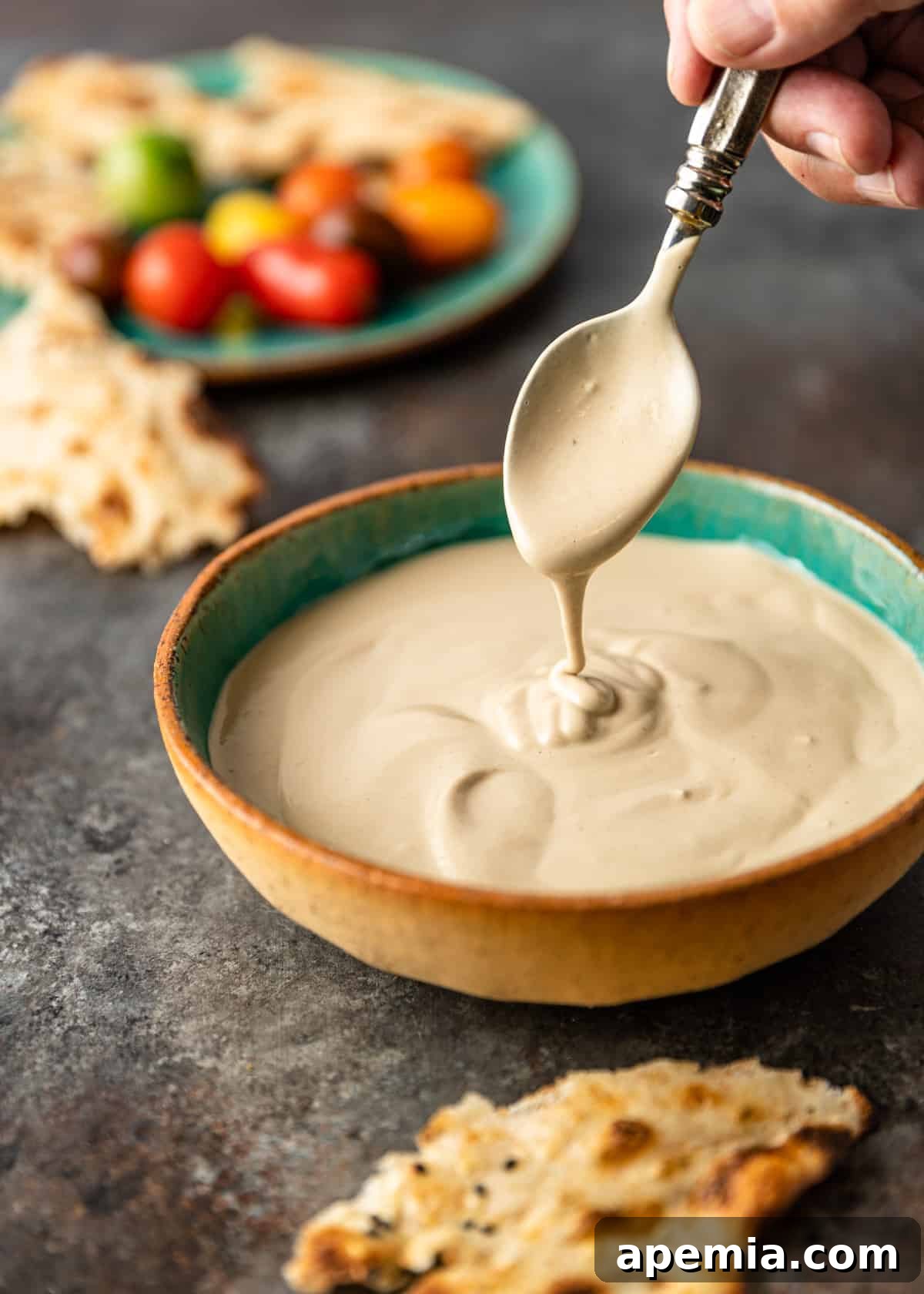 Middle Eastern tahini sauce dripping from a spoon into bowl