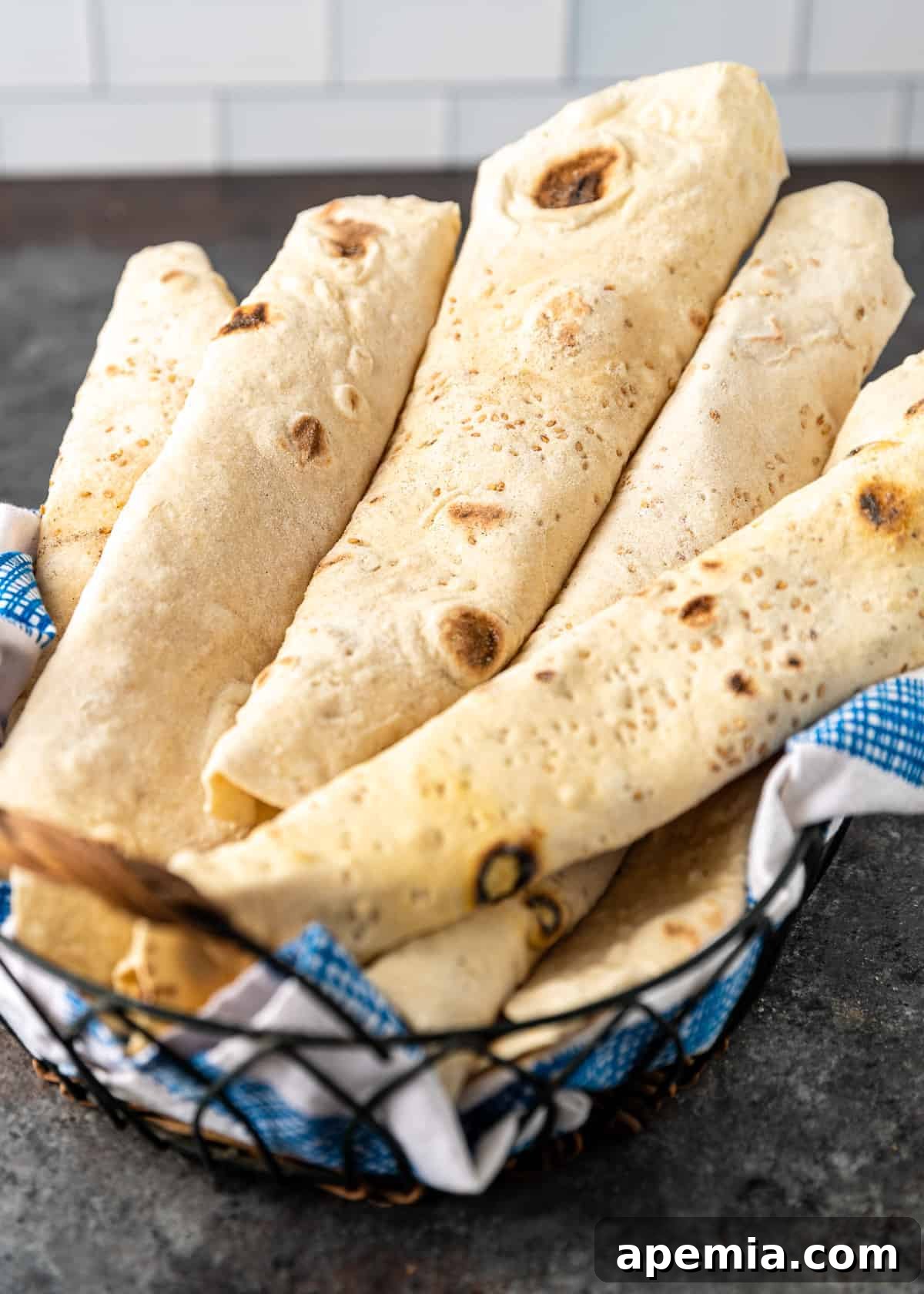 Closeup of a rustic basket filled with golden-brown lavash flatbread, showcasing its inviting texture.