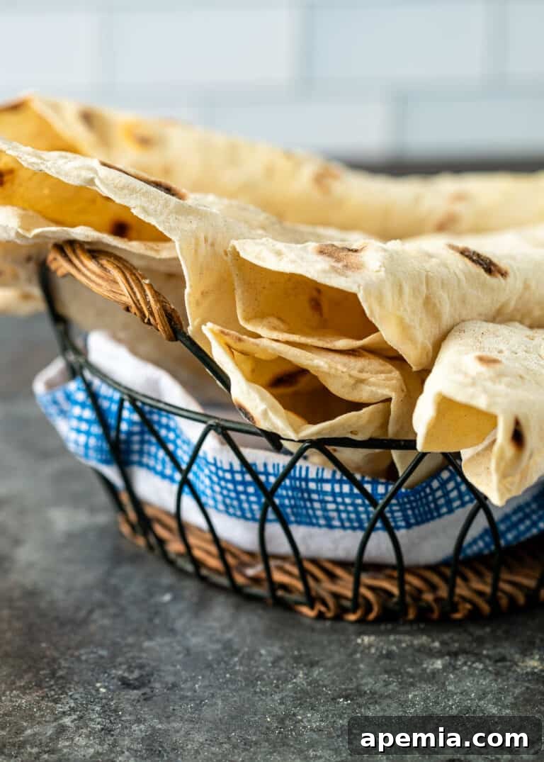 A wicker basket lined with a blue and white towel, holding a stack of freshly made Armenian flatbread, ready to be served.