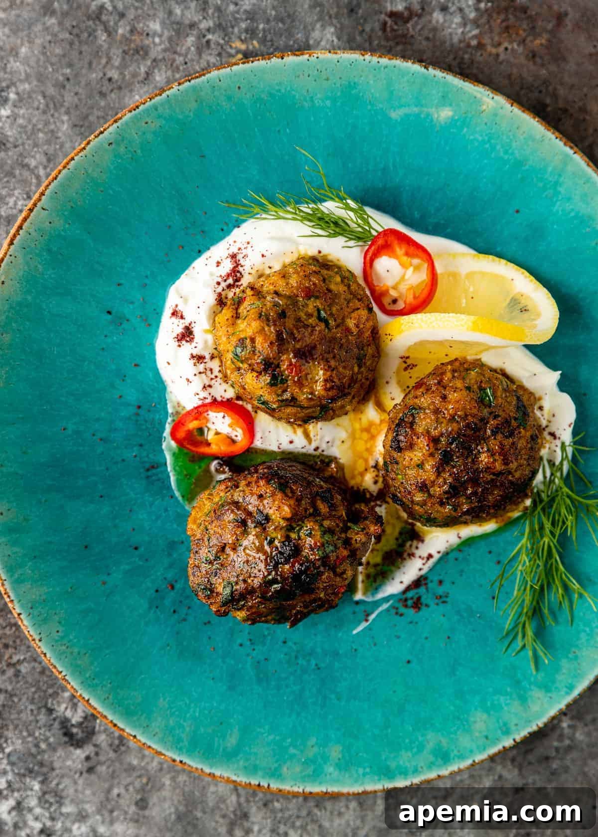 Overhead view of my fish meatball recipe presented on a blue plate, with a delicate sprinkling of sumac for garnish.