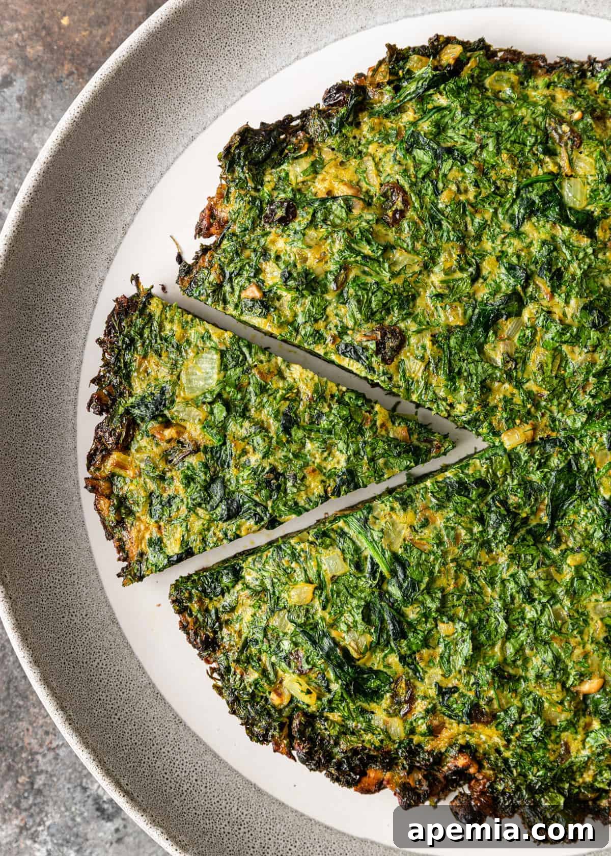 A perfectly portioned slice of Persian herb omelette (Kookoo Sabzi) on a white plate, ready to be enjoyed.