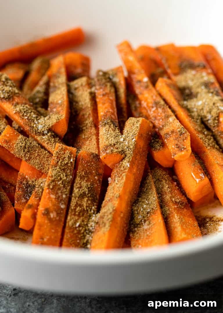 Process shot: carrot sticks evenly coated with a rich blend of Moroccan spices, ready for roasting.