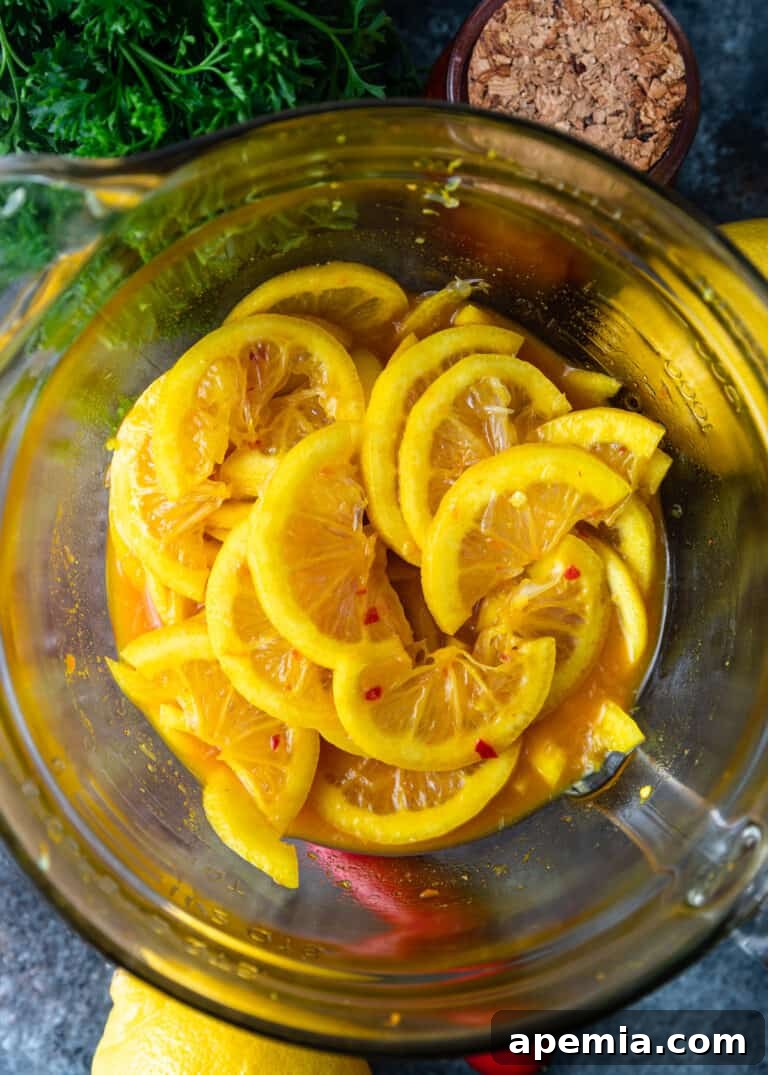 Thinly sliced lemons tossed with a vibrant mix of spices and chili paste in a large glass bowl, illustrating the marination process for quick pickling.