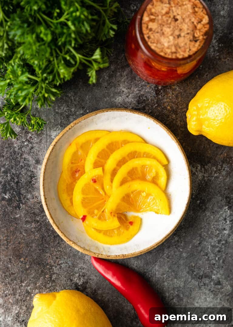An overhead view of a rustic ceramic dish brimming with spicy pickled lemon slices, garnished with fresh herbs, showcasing its readiness to be enjoyed.