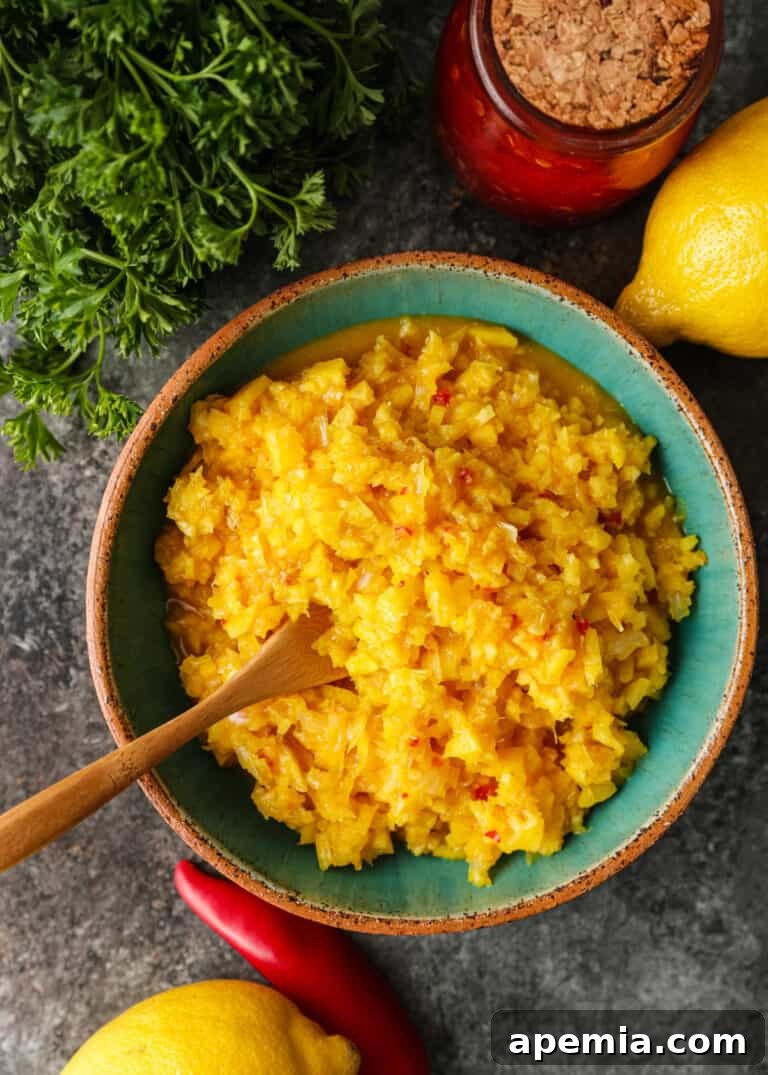 A vibrant Middle Eastern condiment made with pickled lemons, served in an elegant green bowl with a small wooden spoon, highlighting its inviting texture.
