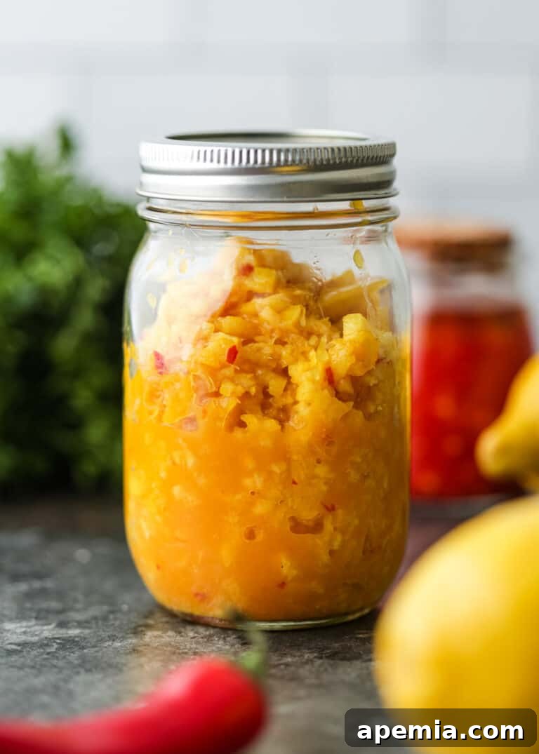 A glass canning jar filled with a rustic, chunky pickled lemon relish, showcasing its preserved beauty and readiness for culinary use.