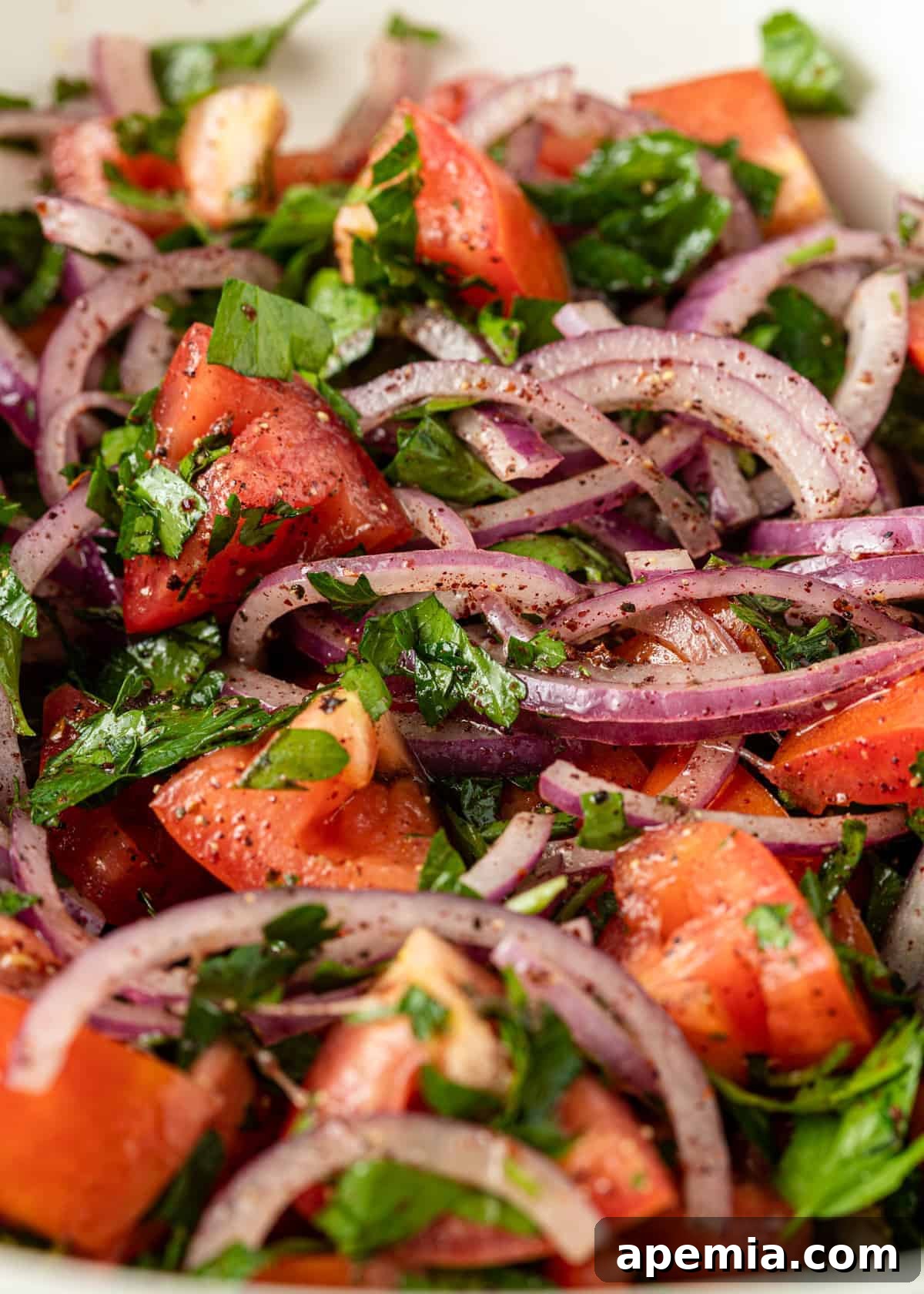 A vibrant close-up of fresh ingredients for white bean salad, including chopped red onion, quartered tomatoes, and roughly chopped Italian parsley, ready for assembly.