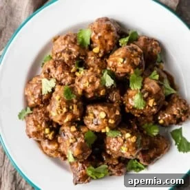 Overhead: homemade lamb meatballs on a white plate, garnished beautifully.