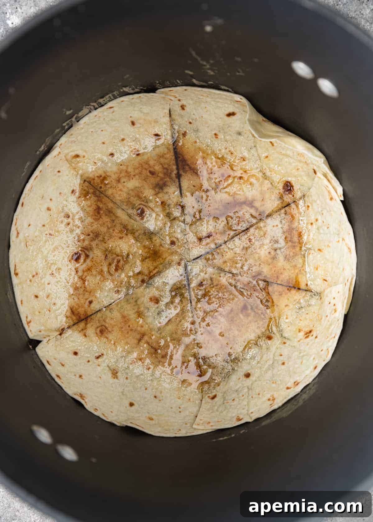 Overhead view: a flour tortilla sliced into six pieces, arranged at the bottom of a skillet, ready for the Tahdig layer.