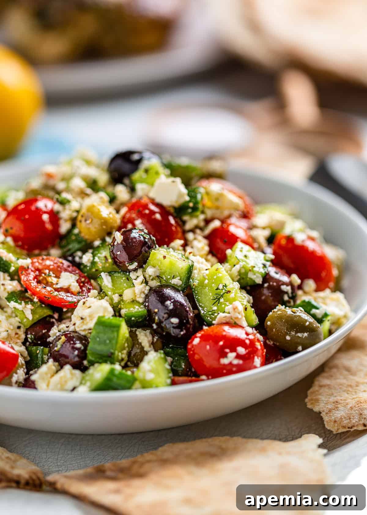 Close-up of a serving of Greek Feta Salad in a white bowl, highlighting the textures and vibrant colors