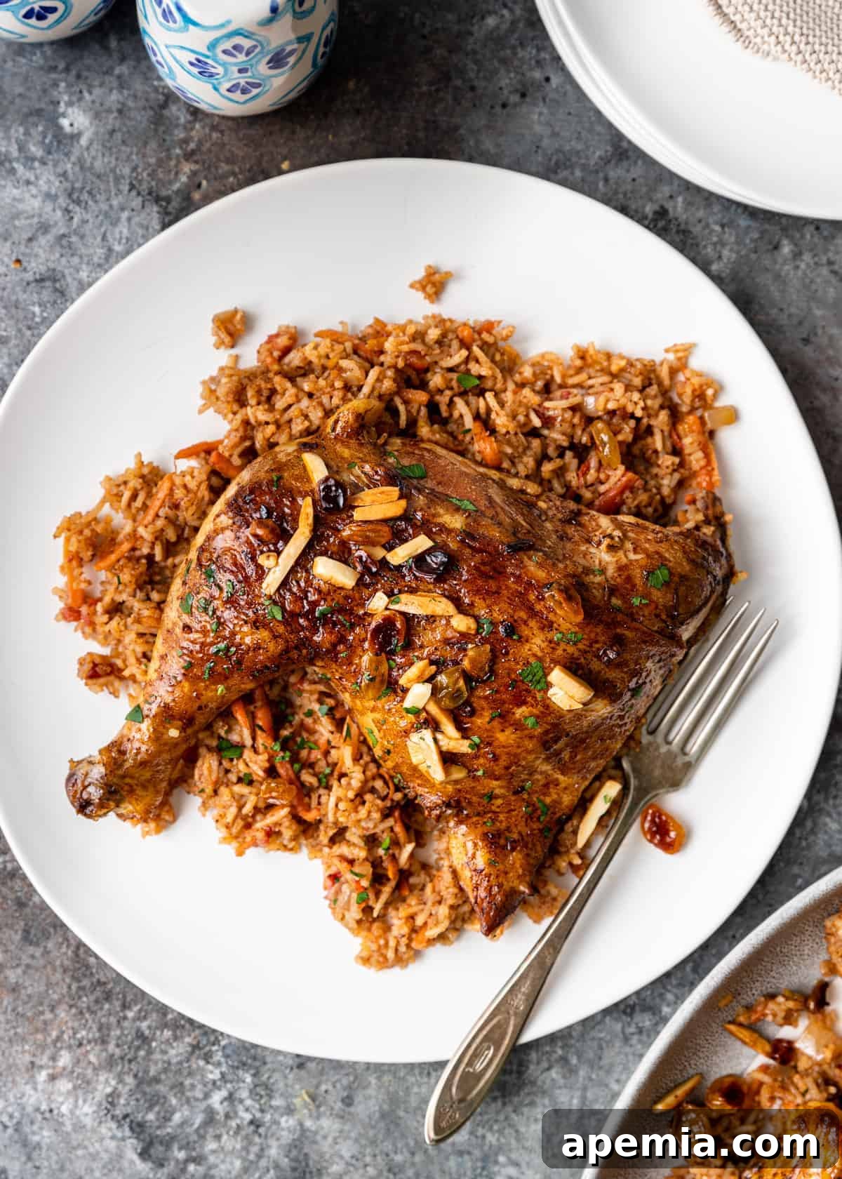 Overhead view of a single serving of Middle Eastern chicken and rice (Kabsa) on a white plate, with a fork ready to enjoy.