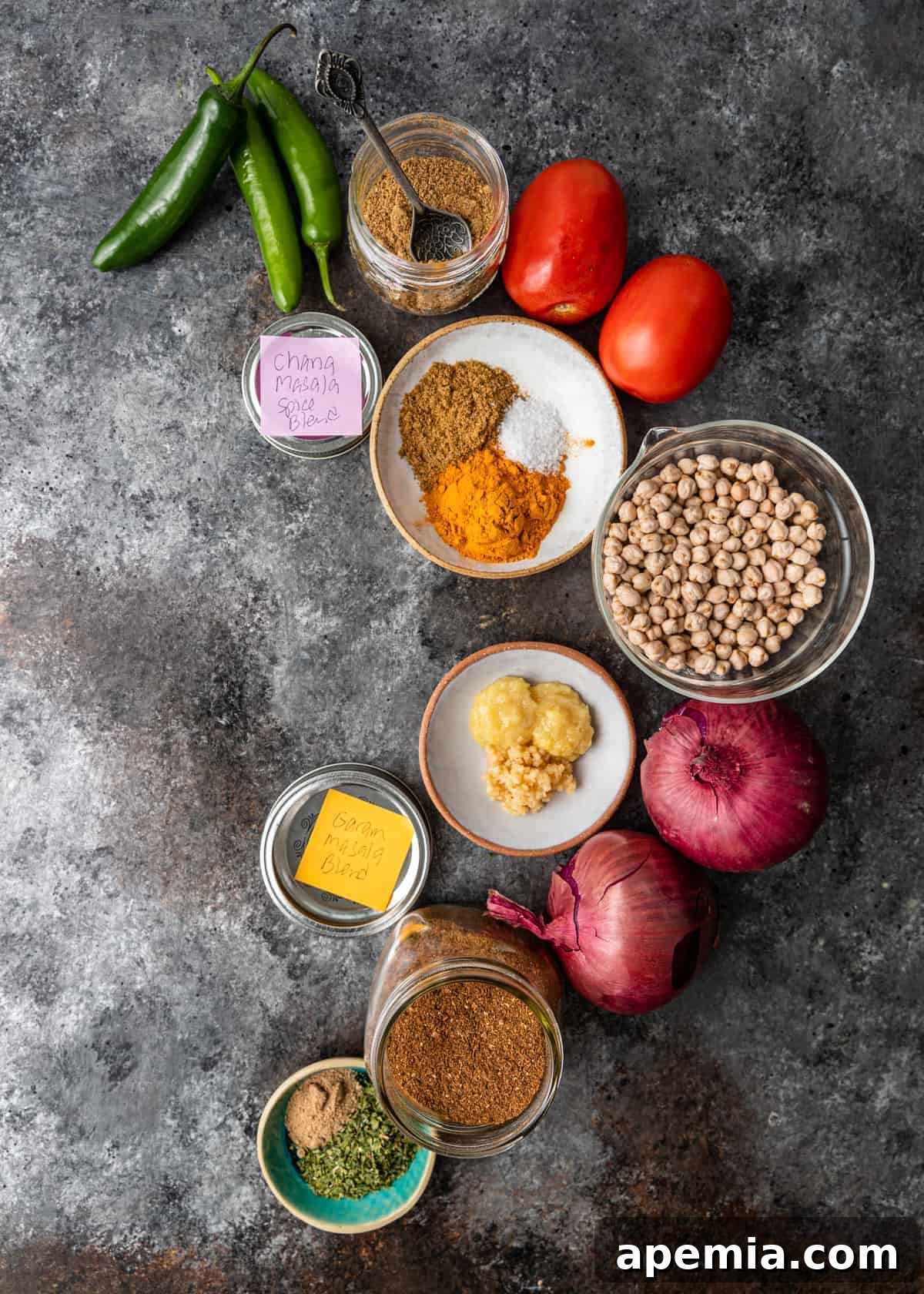 Selection of spices, dried chickpeas, Roma tomatoes, and other fresh ingredients laid out for Instant Pot Chana Masala curry recipe.