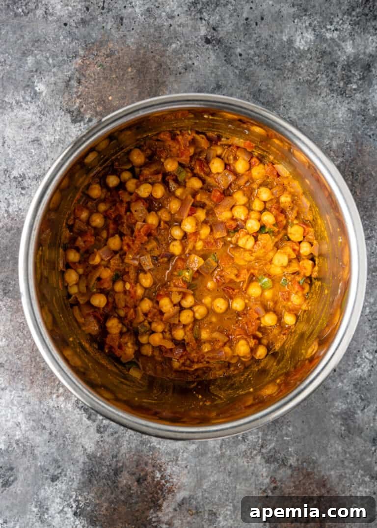 Overhead shot of the Chana Masala Instant Pot recipe cooking in a large pot, with ingredients simmering.