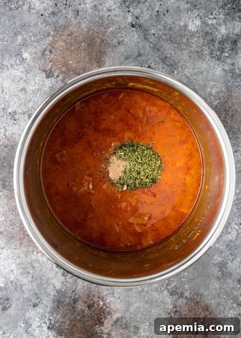 Overhead view of the Indian chickpea masala recipe continuing to cook in a large pot, with rich colors developing.
