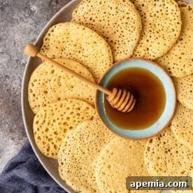 Close up overhead image: platter of semolina pancakes arranged around a bowl of honey