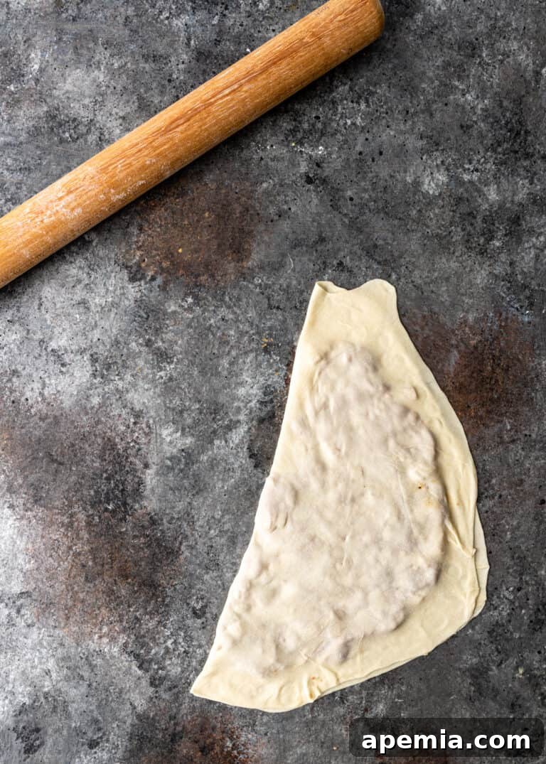 Overhead process shot: Gozleme dough rolled out next to a rolling pin, demonstrating its thinness.