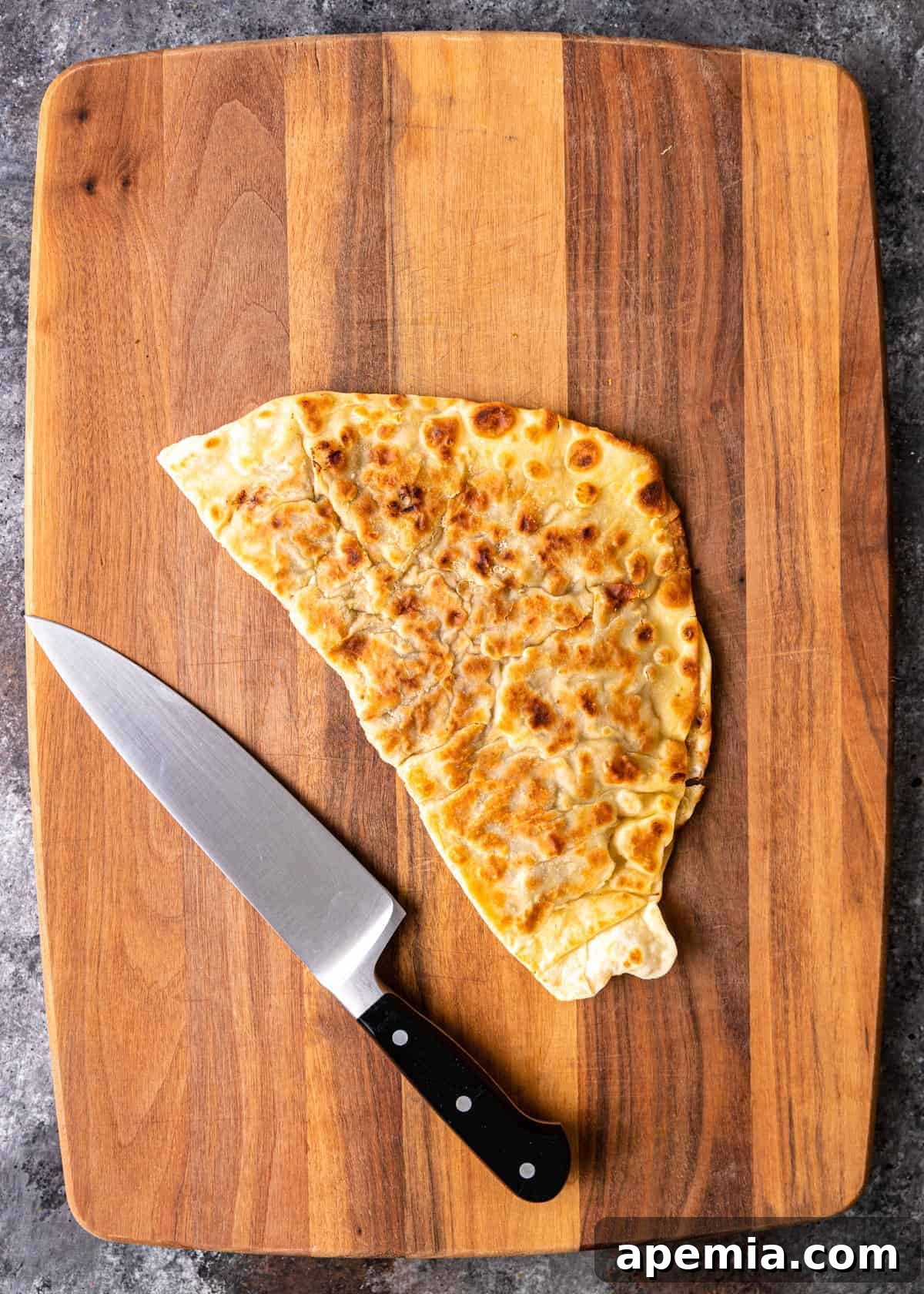 Overhead view of crispy homemade flatbread (Gozleme) on a cutting board with a chef's knife.