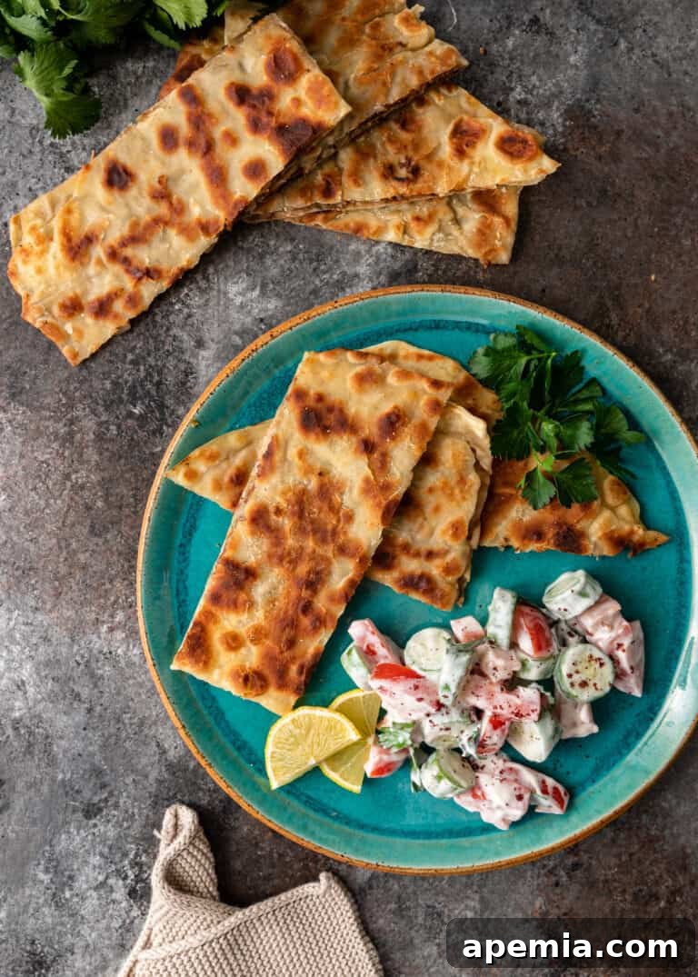 Overhead view of rectangular pieces of crispy Turkish street food (Gozleme) on a plate with a creamy vegetable salad.