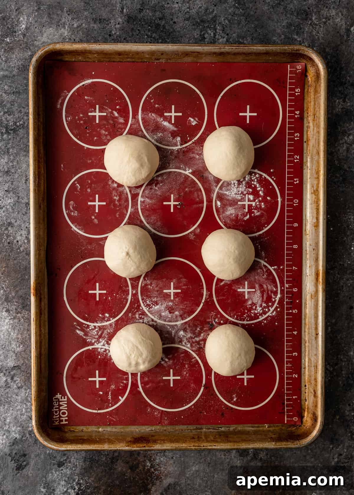 Overhead view of balls of Gozleme bread dough resting on a lined baking sheet, ready to be rolled.