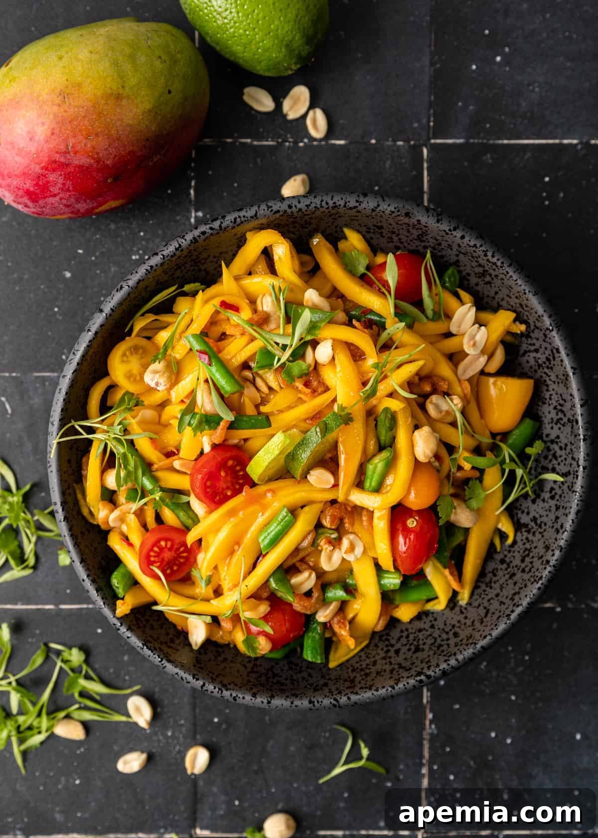 Overhead view of a beautiful Thai mango salad served in an elegant black bowl, ready to be enjoyed.