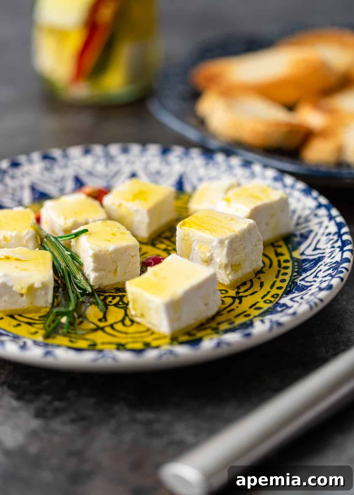 white marinated feta cheese cubes on small appetizer plate with herbs