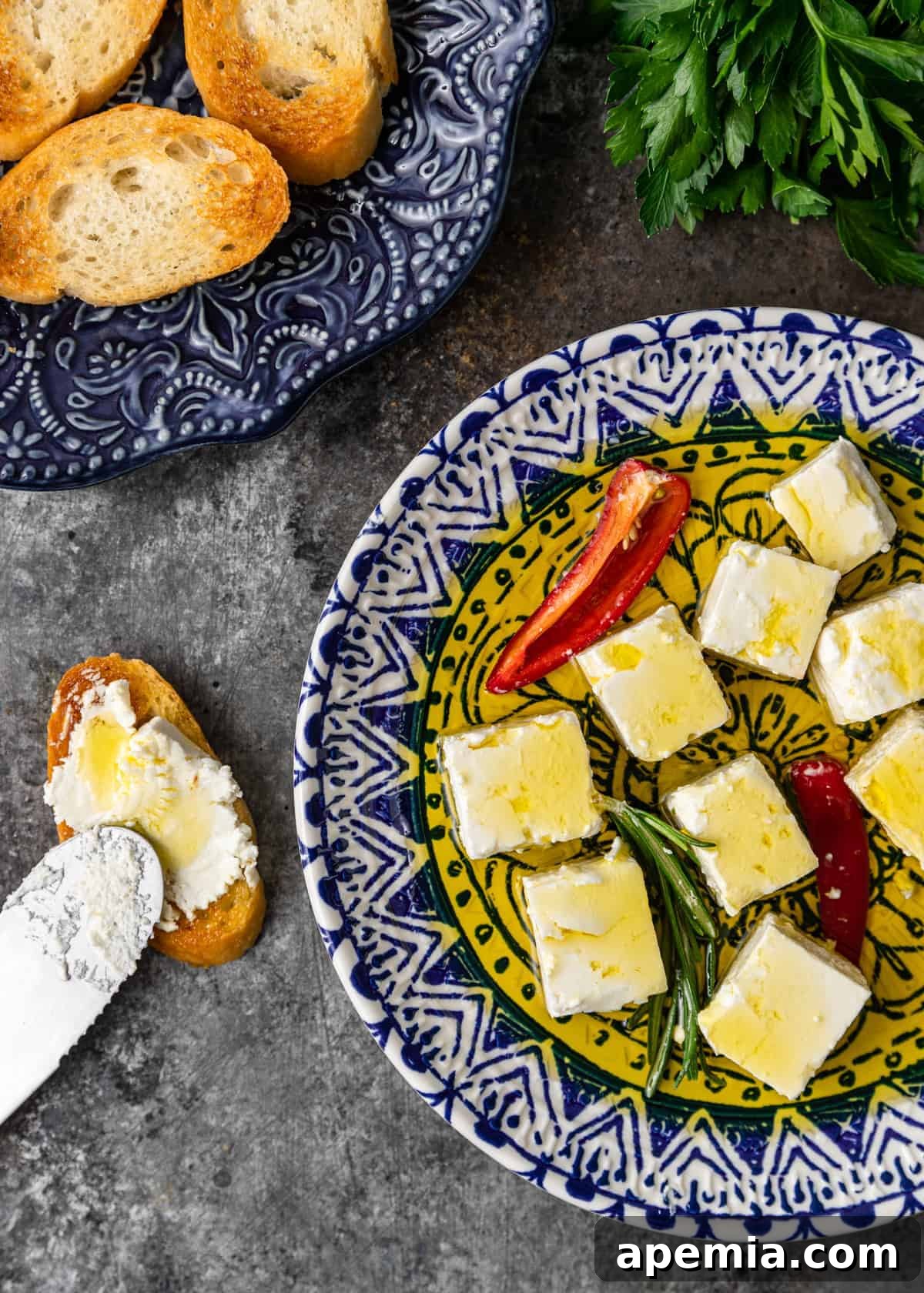 overhead shot of a blue plate with marinated feta, herbs, and chiles