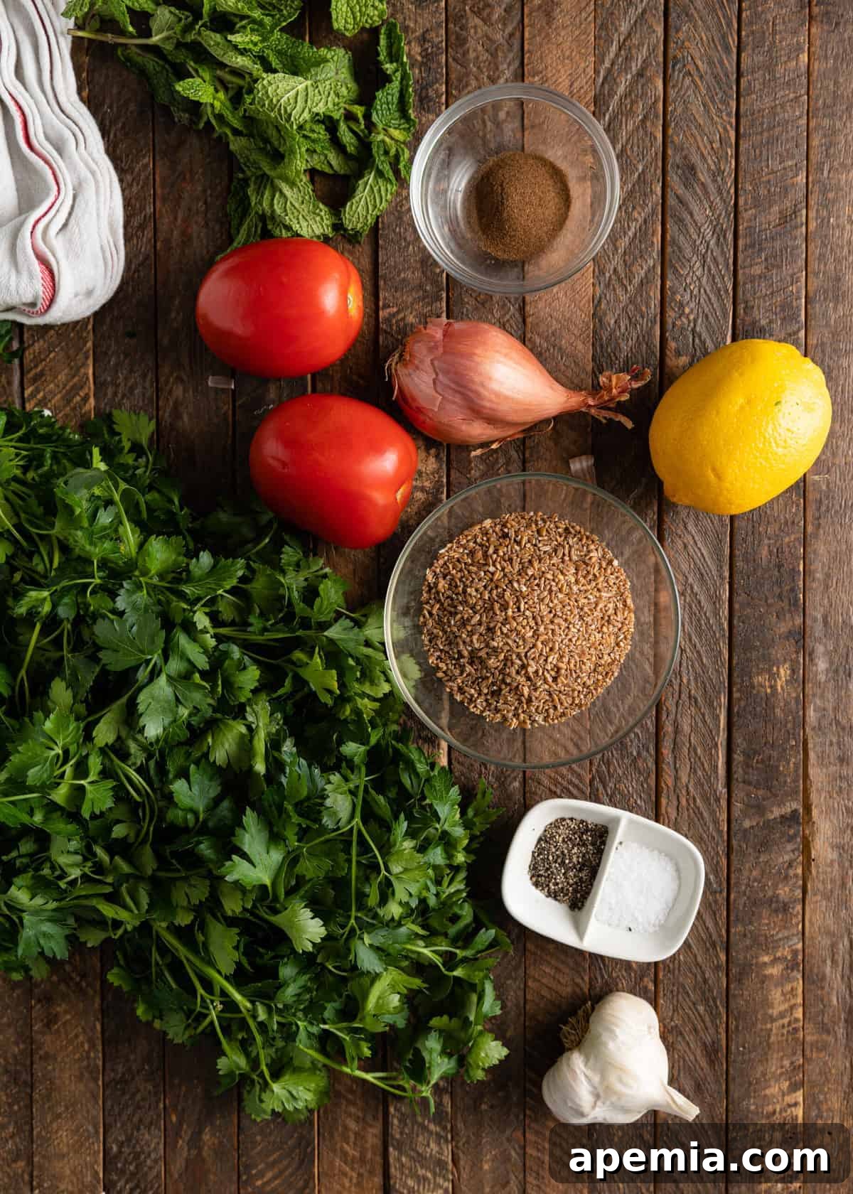 Overhead shot showing fresh herbs, bulgur, tomatoes, and other ingredients laid out for making tabbouleh.