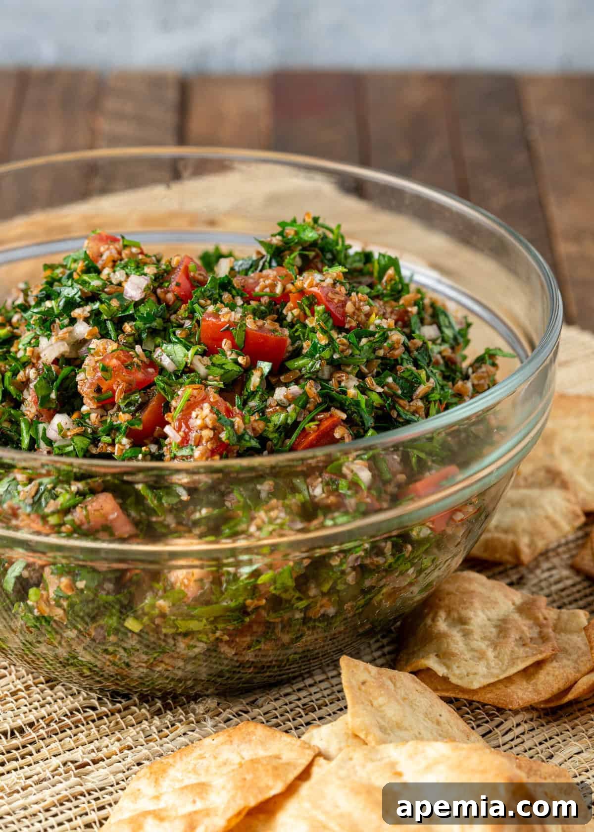 Close-up of a glass bowl brimming with fresh, green tabouli salad, ready to be served.