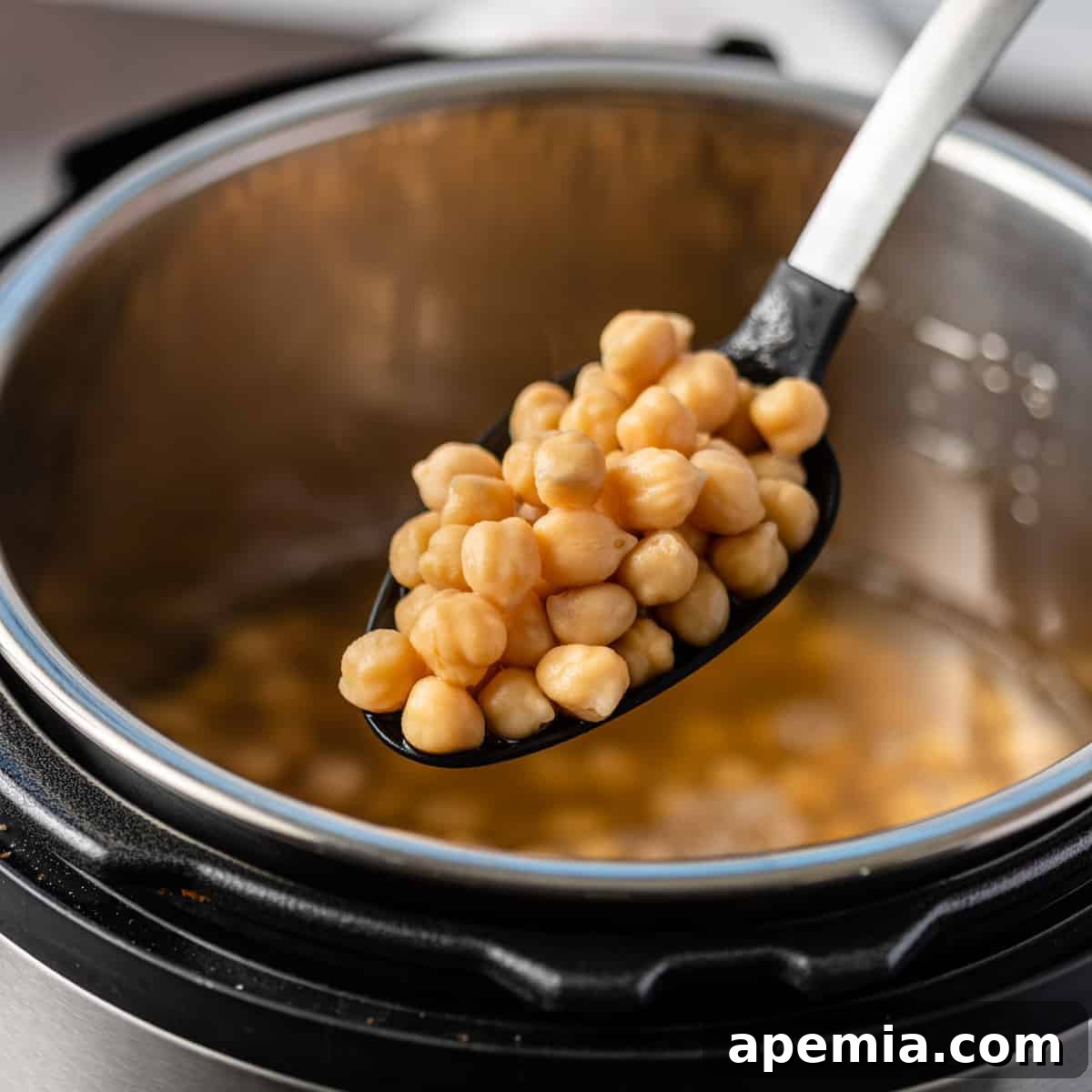 Instant Pot chickpeas on slotted spoon, highlighting perfectly cooked garbanzo beans
