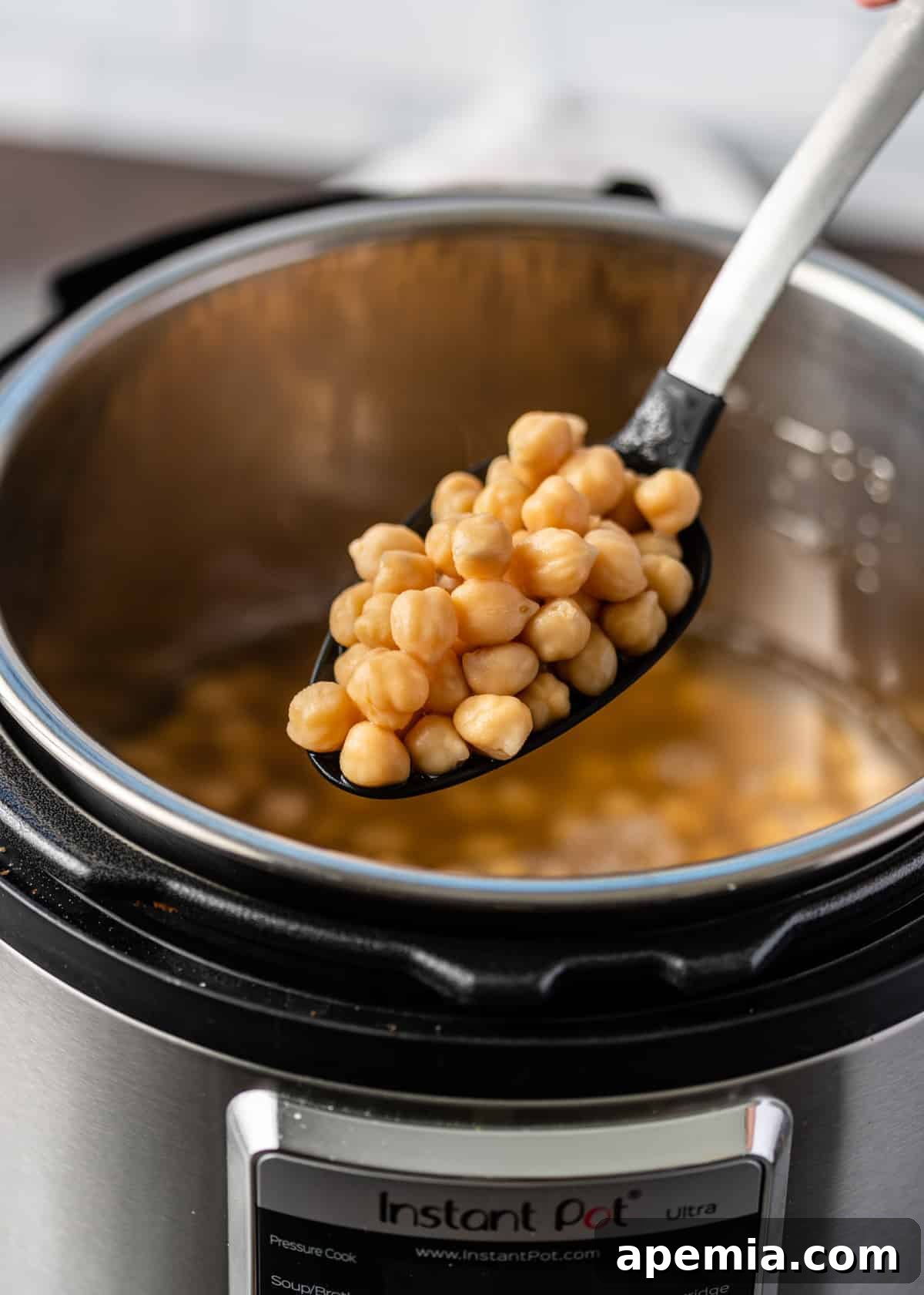 Instant Pot garbanzo beans on a large serving spoon, demonstrating perfectly cooked chickpeas from the pressure cooker