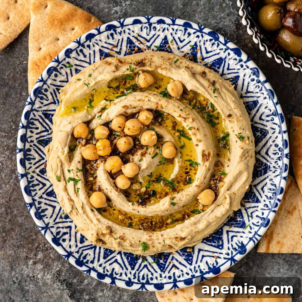 Overhead photo of a bowl of homemade Mediterranean hummus, garnished with olive oil, spices, and whole chickpeas