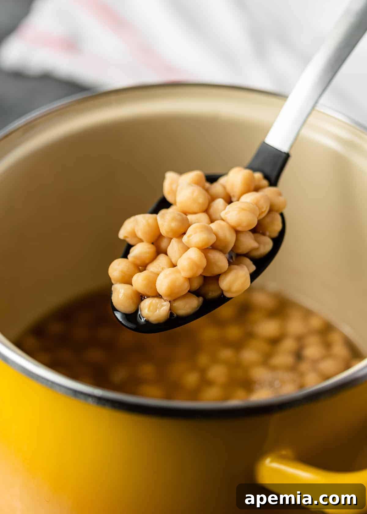Cooking dried garbanzo beans in a large yellow pot on the stovetop, a traditional and effective method