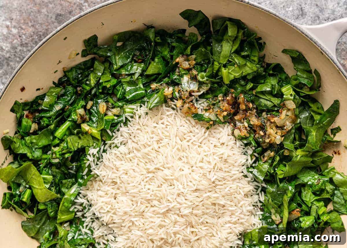 A large sauté pan on a stovetop, showing spinach, rice, and minced garlic being sautéed together, just beginning to wilt and release their aromas.