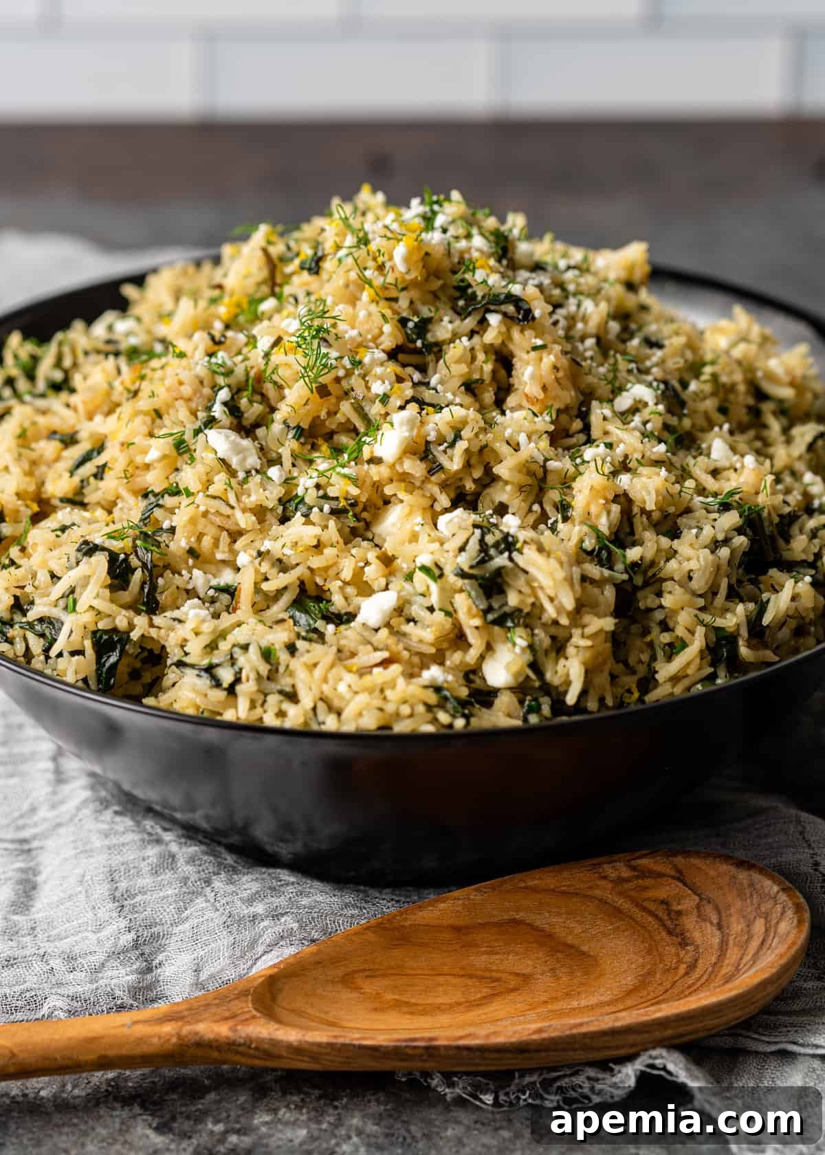 A side view of a serving of Mediterranean rice dish, Spanakorizo, presented in an elegant black bowl, highlighting its texture and inviting appearance.