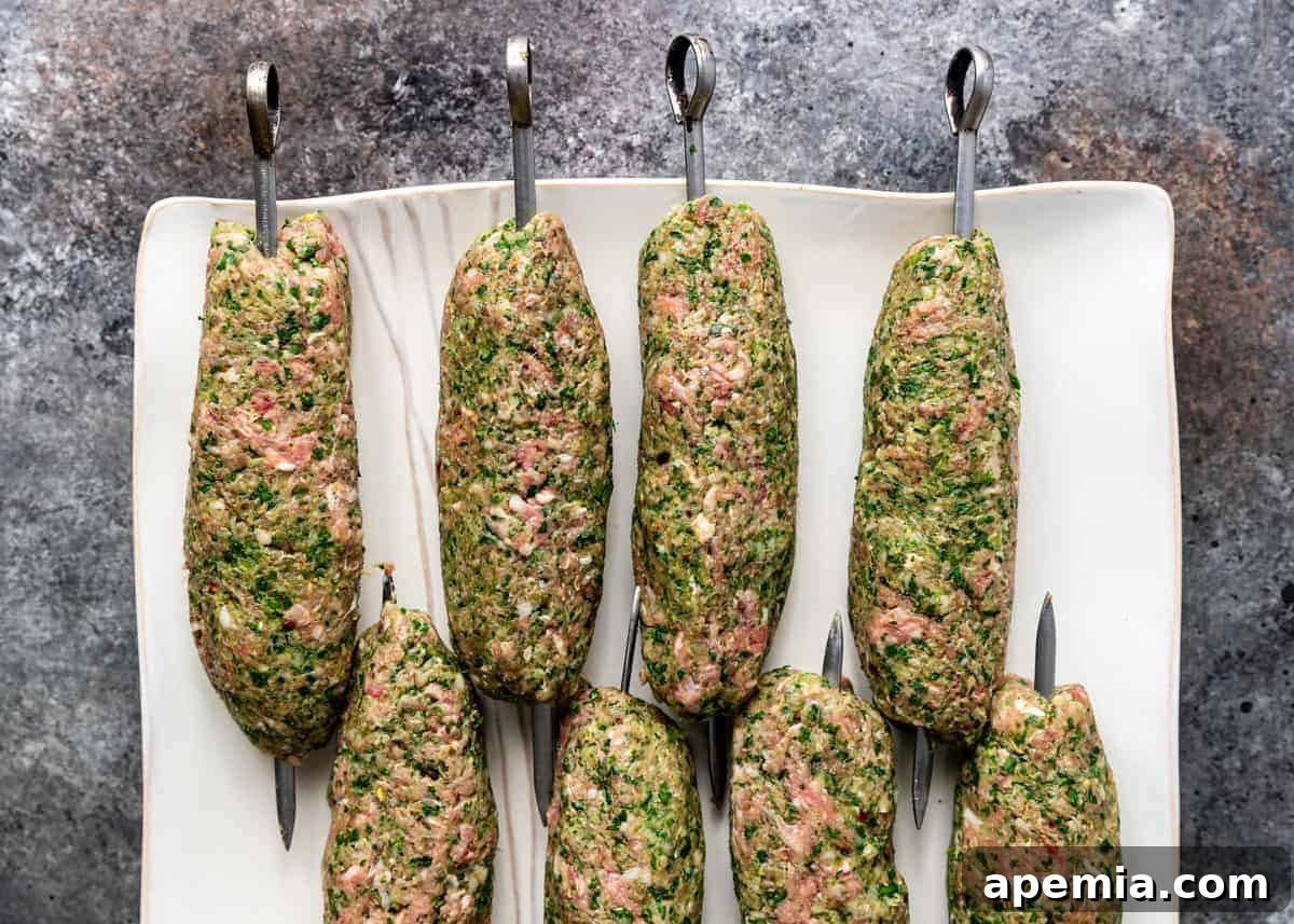 Uncooked mixture of ground beef and North African spices expertly formed around metal kabob skewers, ready for the grill.