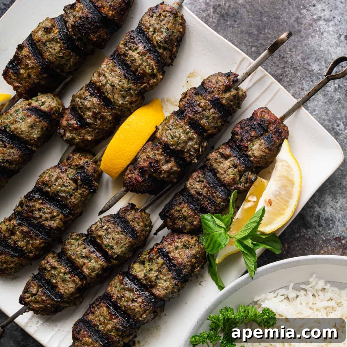 Perfectly grilled ground beef kefta, still shaped around metal skewers, glistening with juices and ready to be served.