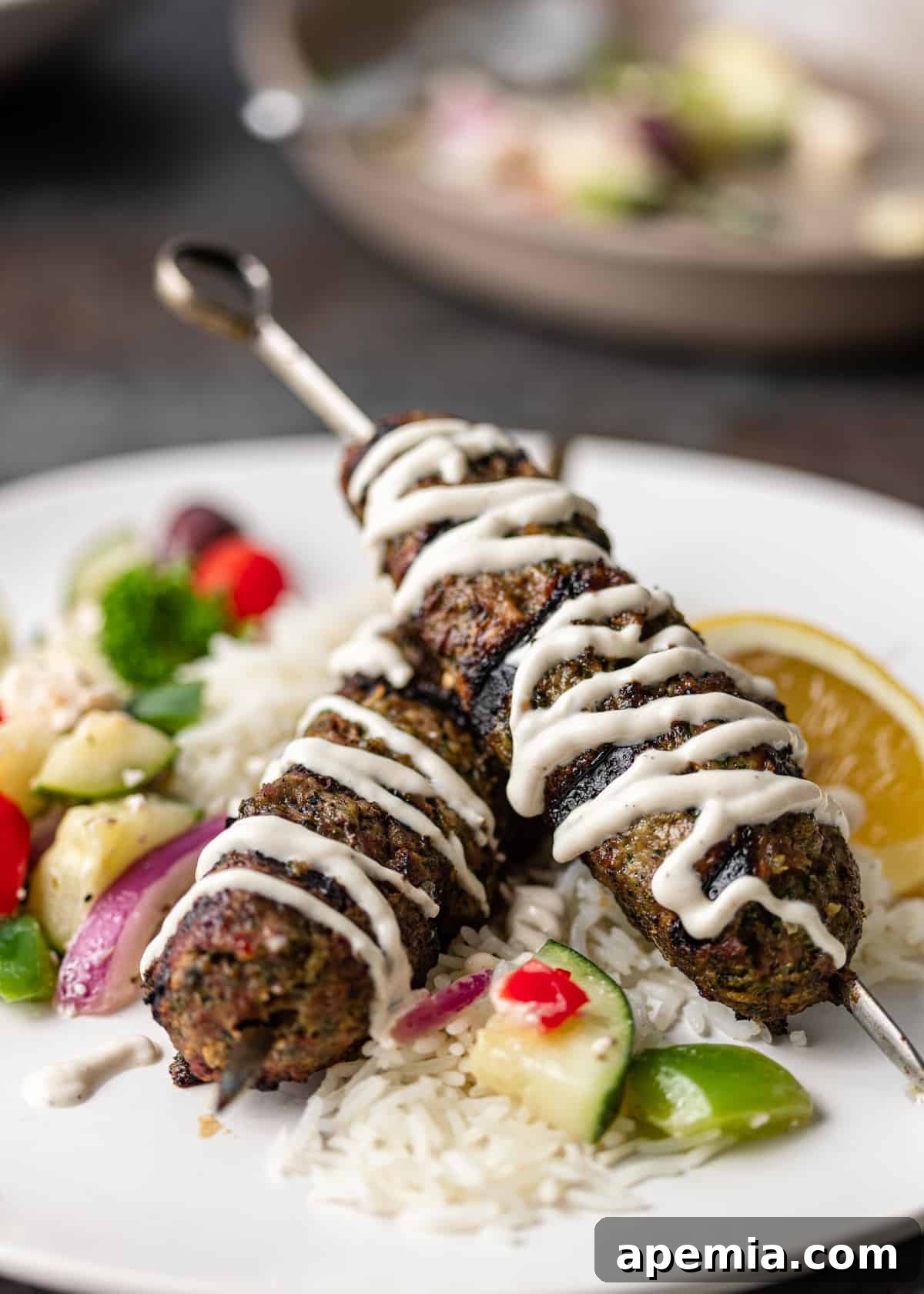 Moroccan ground beef kabobs beautifully plated on metal skewers, with a side of couscous and fresh herbs, ready to be enjoyed. The image captures the inviting colors and textures of the dish.