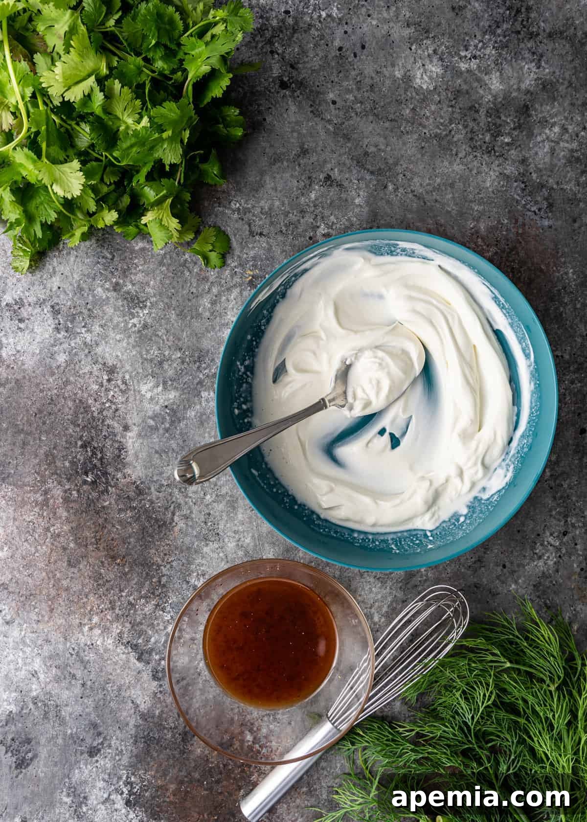 A bowl of creamy Greek yogurt positioned next to a small bowl of the golden honey marinade, illustrating the two key components of the dressing.